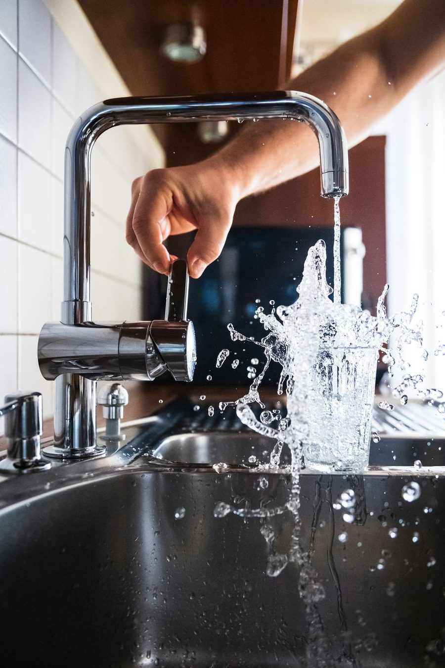 Tap water splashing into a glass at a kitchen faucet